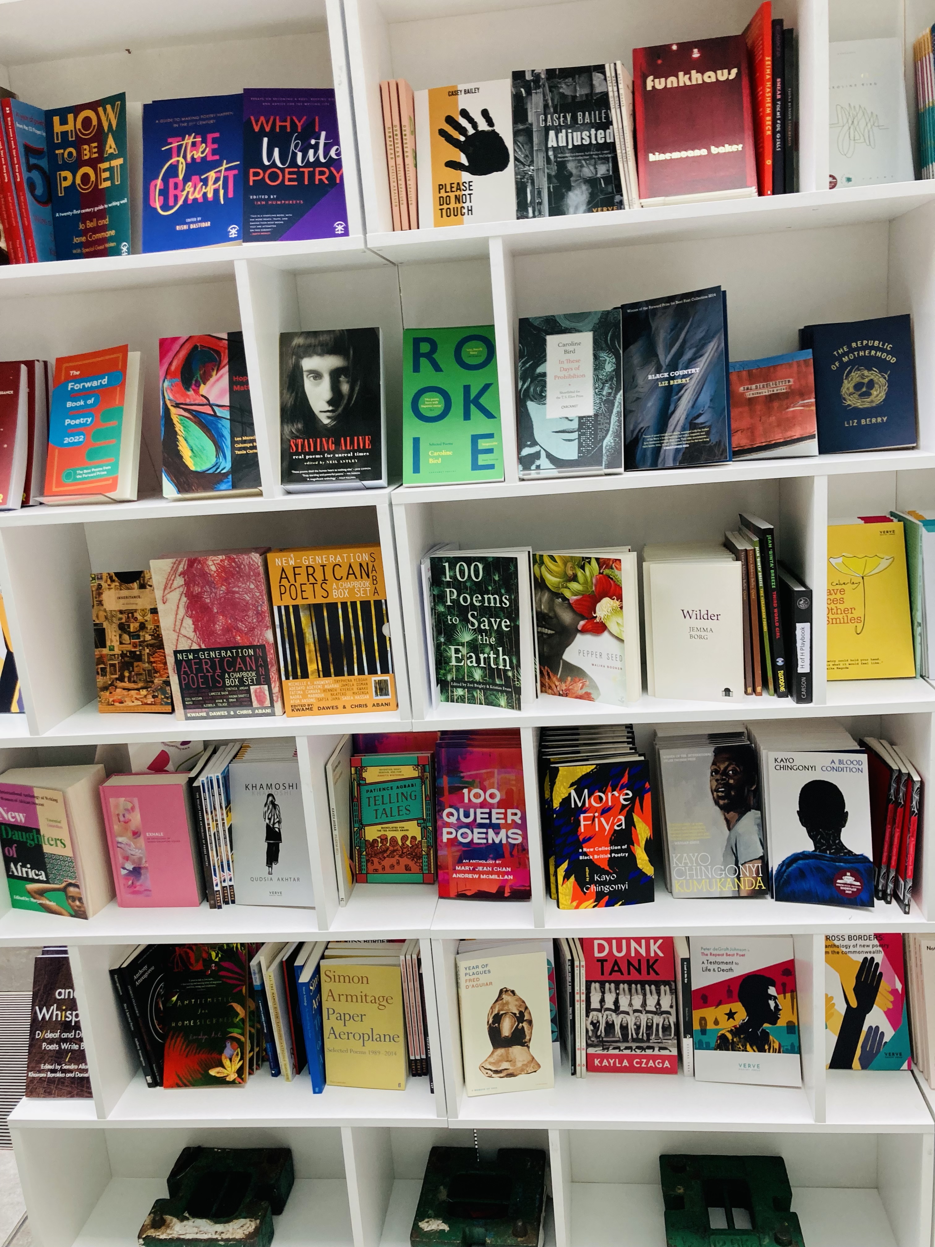 A white bookshelf/display containing lots of multicoloured poetry collections, displayed at the Verve/BBC contains strong language festival.